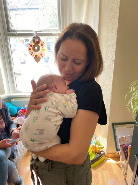 An adult holding a newborn close at home