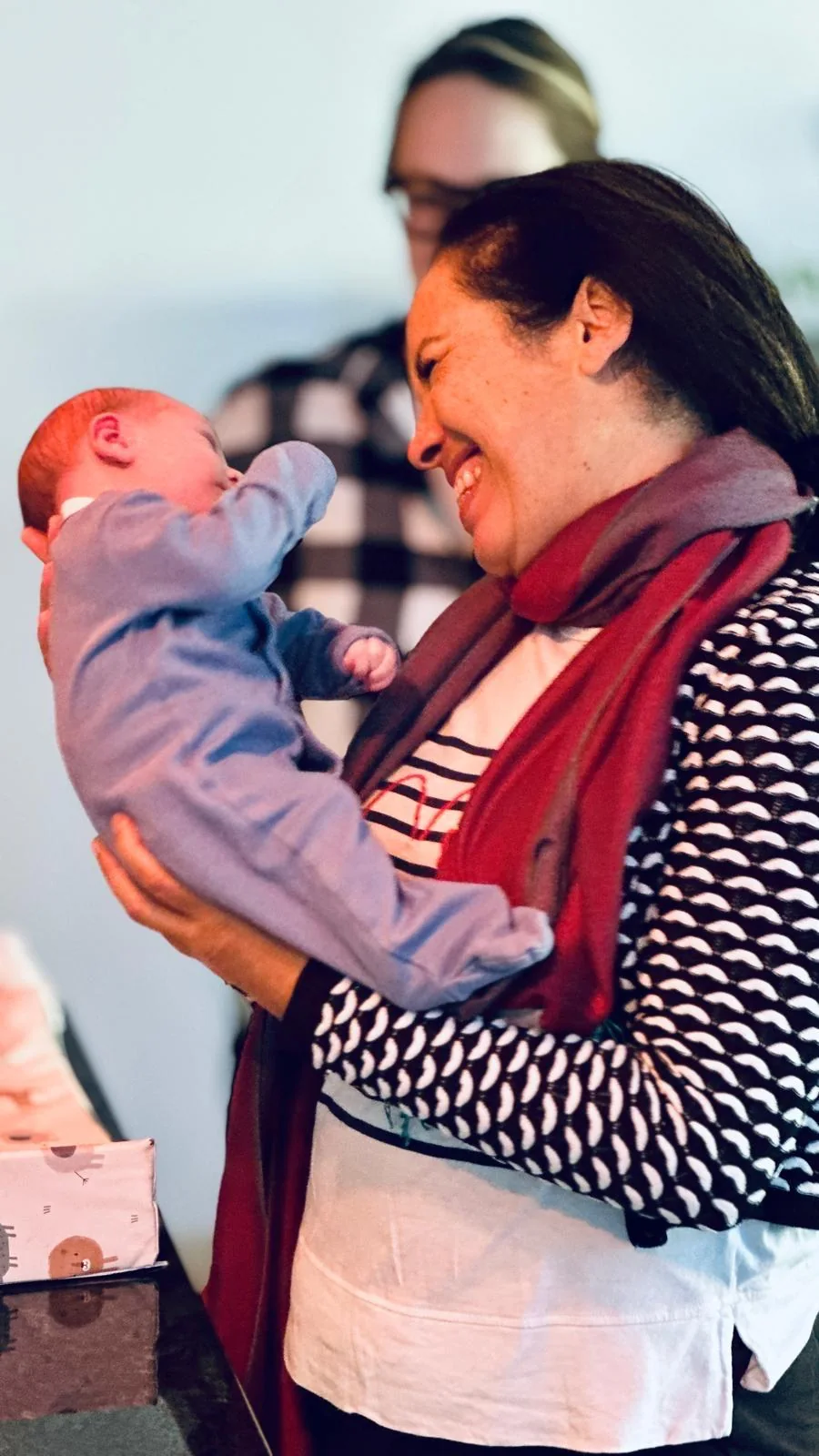 Regina smiling at a newborn she is holding